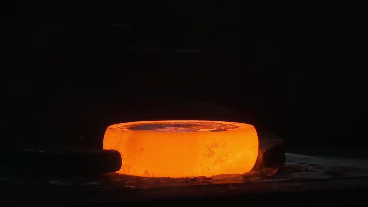 Heated metal being formed under a forging press