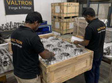 Two staff members handling flanges arranged on a wooden crate