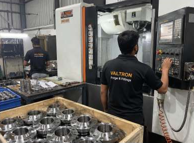 Operator at a machining centre beside trays of metal components