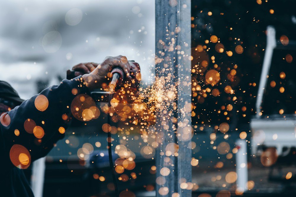 Worker using an angle grinder on a metal structure with sparks at the contact point